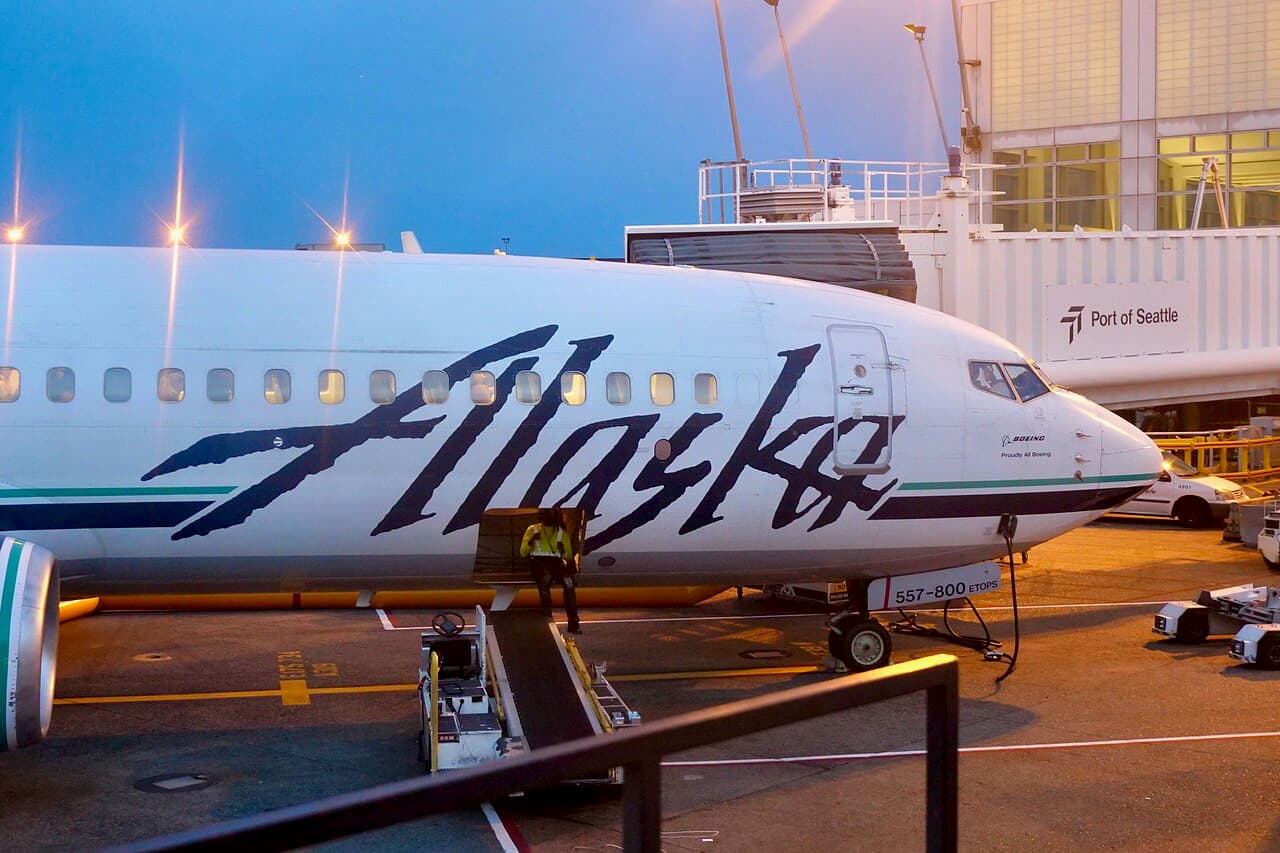 An Alaska Airlines aircraft on the runway at sunset, preparing for international flight