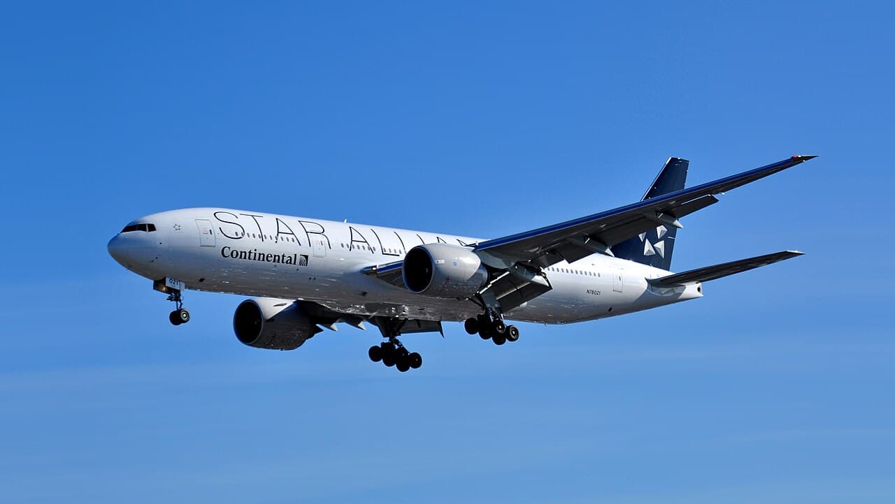 A Boeing 777X prototype with extended wingtips on an airport runway during testing.