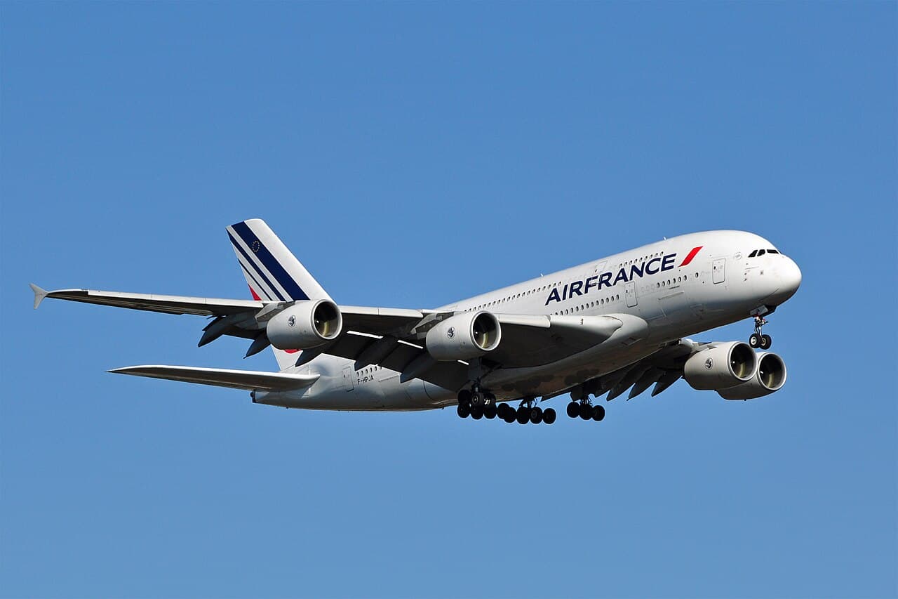 Airbus A380 taxiing on runway with maintenance crews inspecting wing
