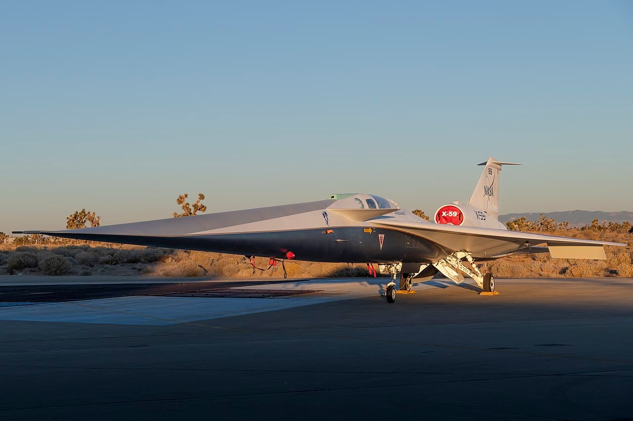 NASA X-59 experimental aircraft flying against a clear blue sky during a test flight